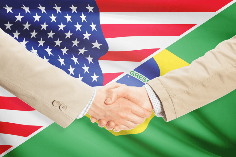 Handshake in front of overlapping United States and Brazilian flags