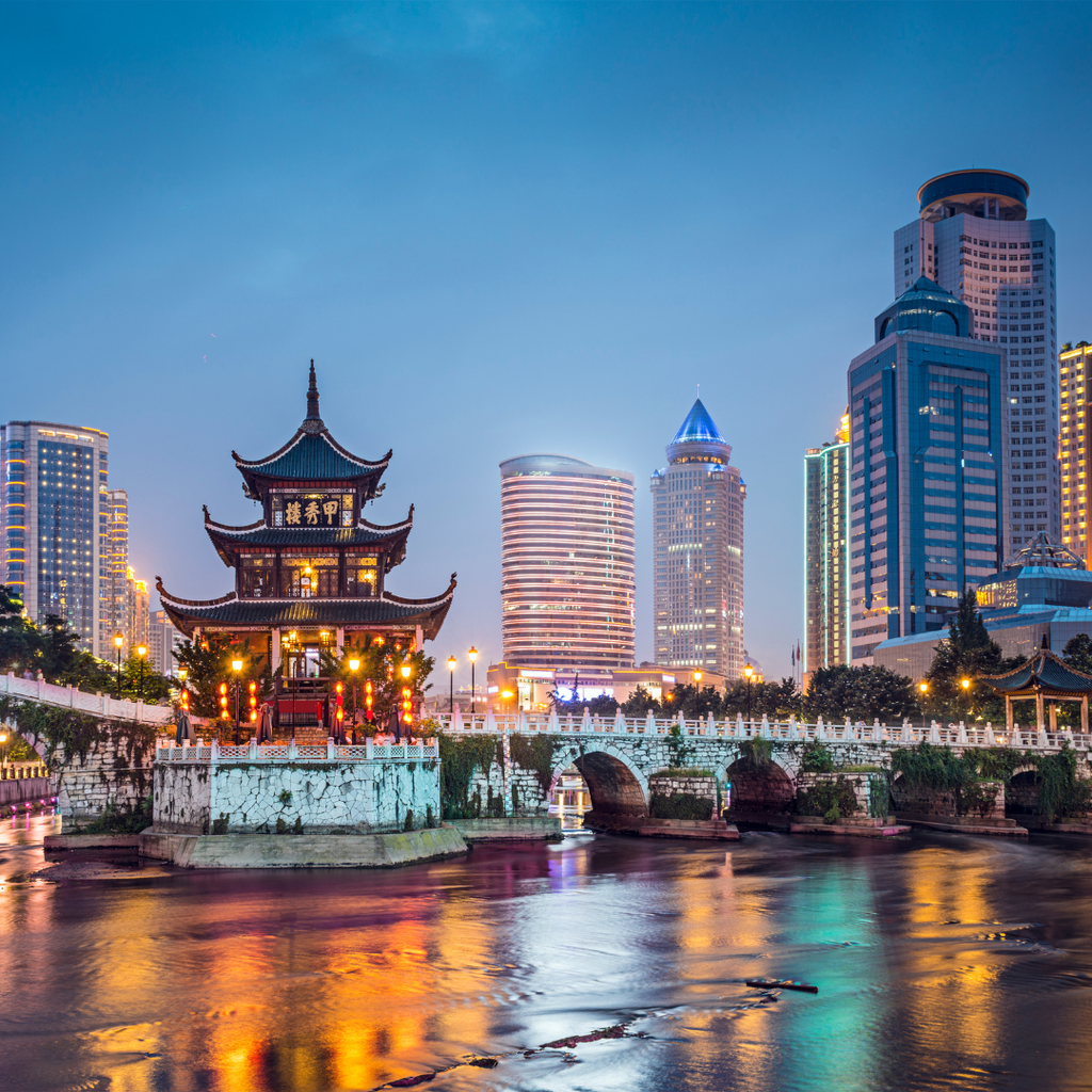 Jiaxiu Tower and the Guiyang skyline lit at dusk above the river