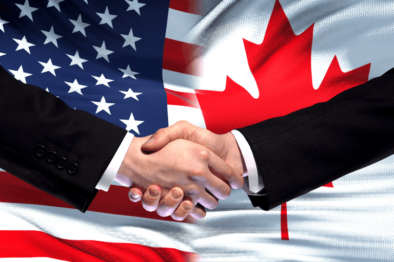 Handshake in front of overlapping United States and Canadian flags