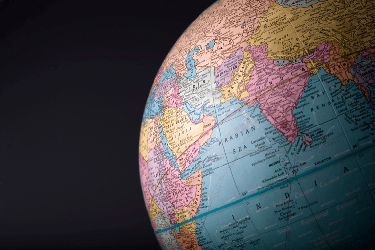 Close-up of a vintage globe showing the Middle East, India and the Arabian Sea against a dark background